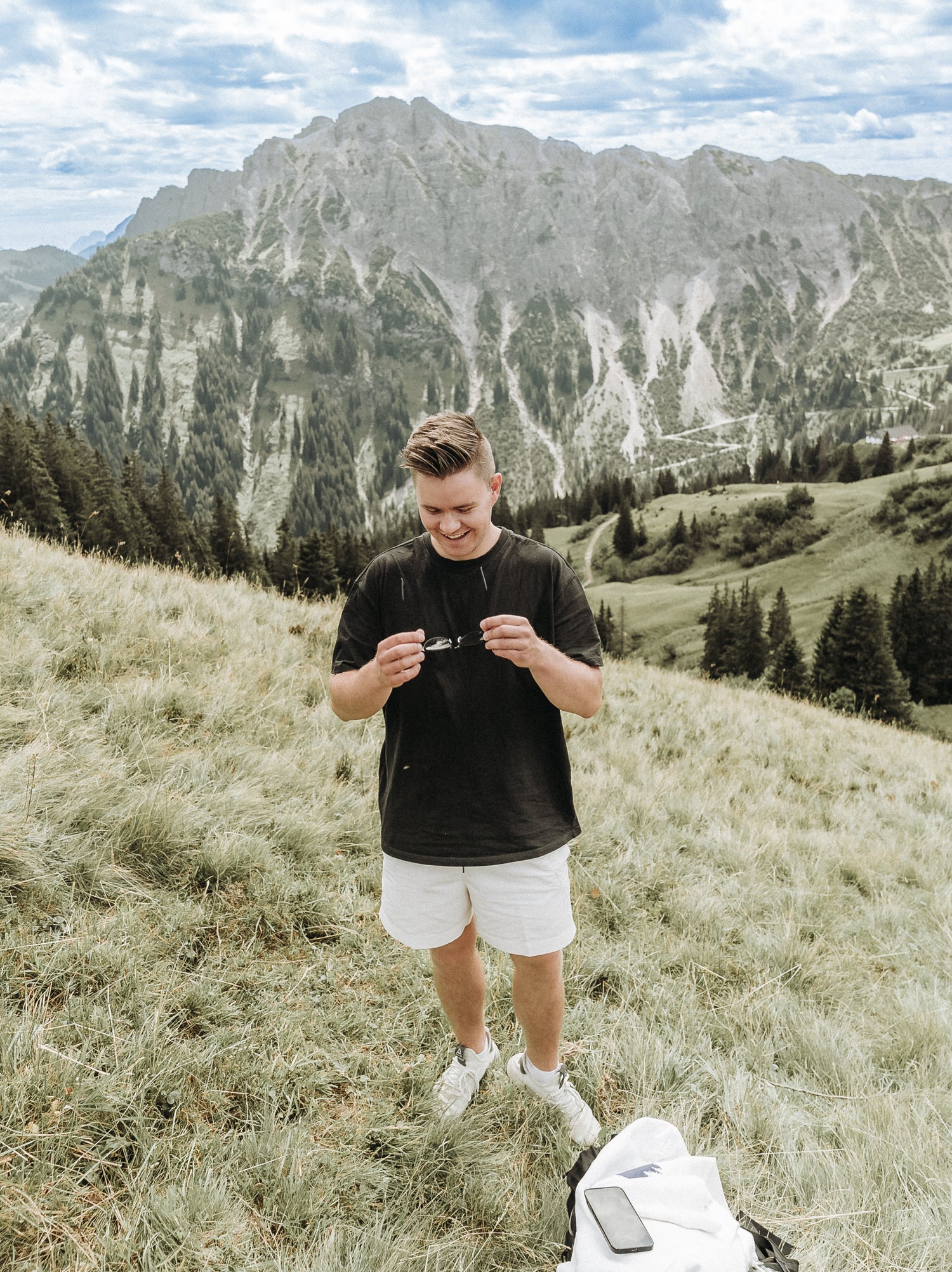 Berge in Tirol mit einem jungen lachenden Mann im Fokus mit Sonnenbrille